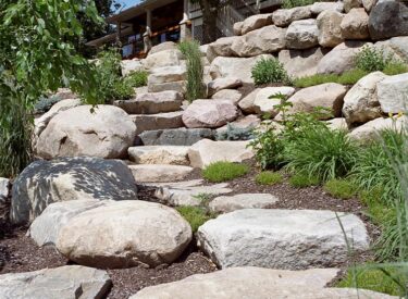 Natural stone stairway leading up to boulder retaining wall