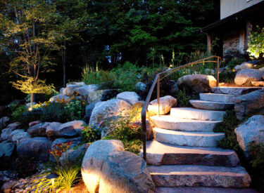 Boulder retaining wall, stone steps lighted at night