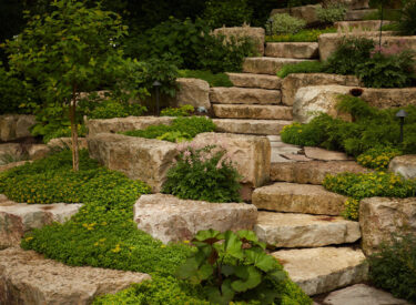 boulder retaining wall with stone steps and plants 4