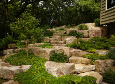 boulder retaining wall with stone steps and plants